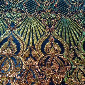 May include: A dark blue fabric with a gold and iridescent sequin pattern. The pattern features a repeating design of ornate swirls and leaves.