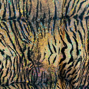 May include: A close-up of a brown and black tiger print fabric with iridescent glitter. The fabric has a shimmery, holographic effect.