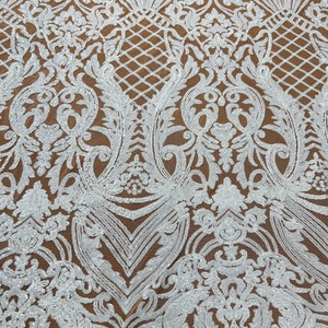 May include: White sequined fabric with a brown mesh backing. The sequins are arranged in a floral pattern.