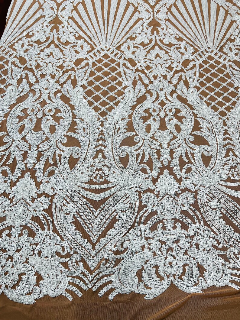 May include: White sequined fabric with a brown mesh backing. The sequins are arranged in a floral pattern.