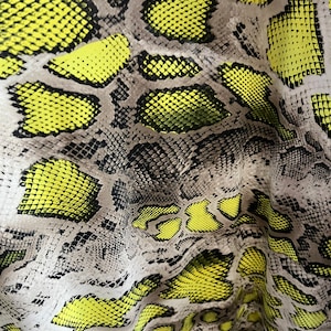 Könnte beinhalten: Nahaufnahme eines Stoffes mit Schlangenhautmuster. Der Stoff ist hellbraun mit einem gelben Schlangenhautmuster.