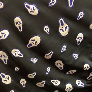 May include: Black fabric with a repeating pattern of white ghost faces with blue outlines. The ghost faces are all screaming.