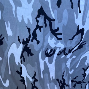 May include: A camouflage pattern fabric with a white, grey, and black colour scheme. The pattern is abstract and resembles a swirling, organic design.