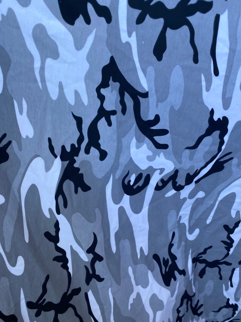 May include: A camouflage pattern fabric with a white, grey, and black colour scheme. The pattern is abstract and resembles a swirling, organic design.