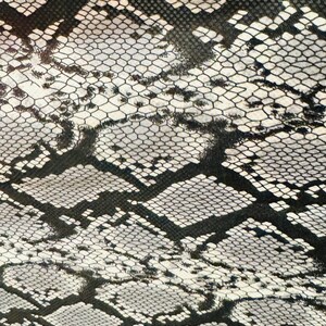 May include: Black and white snakeskin pattern fabric with a textured surface.