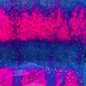 Op de afbeelding: Een close-up van een iriserende stof met een blauwe, roze en paarse kleurverloop. De stof heeft een textuur met een rasterpatroon.