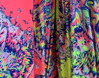 May include: Close-up of a fabric with a colorful abstract pattern. The fabric is pink, yellow, blue, and green. The pattern is made up of swirls and circles.