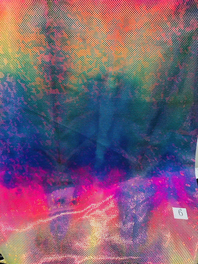 Op de afbeelding: Een close-up van een iriserende stof met een regenboogpatroon en een klein wit label met het nummer "6" erop.