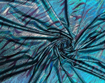 May include: Close-up of a teal and black iridescent fabric with a swirling pattern. The fabric has a shimmery, metallic finish.