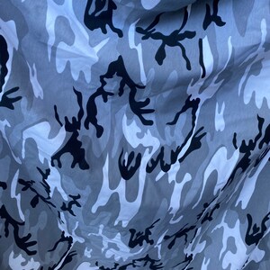 May include: Grey and black camouflage fabric with a wavy pattern. The fabric is folded and has a soft, textured feel.