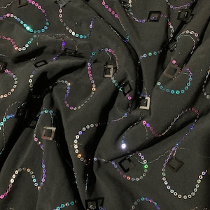New poly black spandex with hanging iridescent sequins 2-way stretch 58/60” Sold by the YD. Ships worldwide from Los Angeles California USA.
