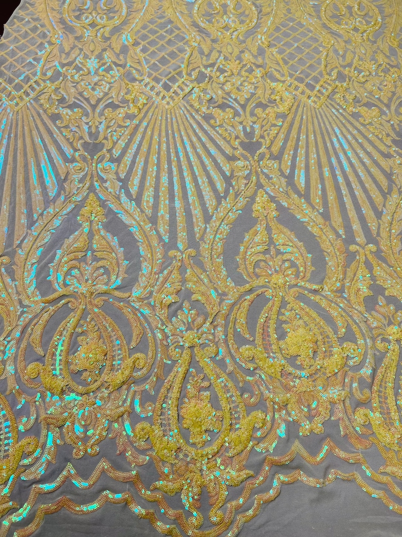 May include: Yellow iridescent sequins on a mesh fabric with a damask pattern. The sequins are arranged in a repeating pattern of swirls and leaves.
