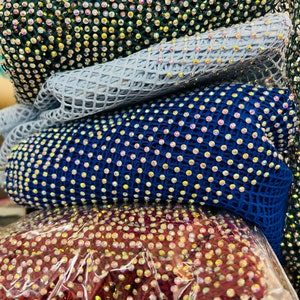 May include: Four rolls of mesh fabric with iridescent rhinestones. The fabric is in shades of green, blue, and burgundy.
