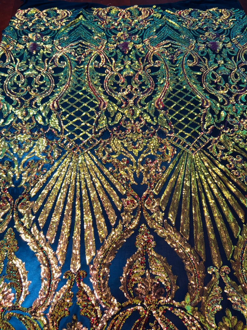 May include: Black fabric with a gold and green iridescent sequin pattern. The pattern features a damask design with a repeating floral motif.