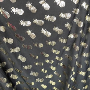 May include: Black fabric with a repeating pattern of gold pineapple silhouettes.