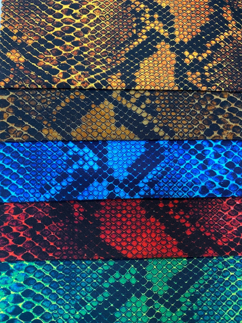 May include: Five fabric swatches with a snake skin pattern. The swatches are in the colours brown, black, blue, red, and green.