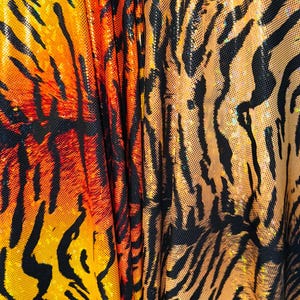Puede incluir: Primer plano de una tela con estampado de tigre. La tela es naranja, negra y dorada con un acabado brillante.