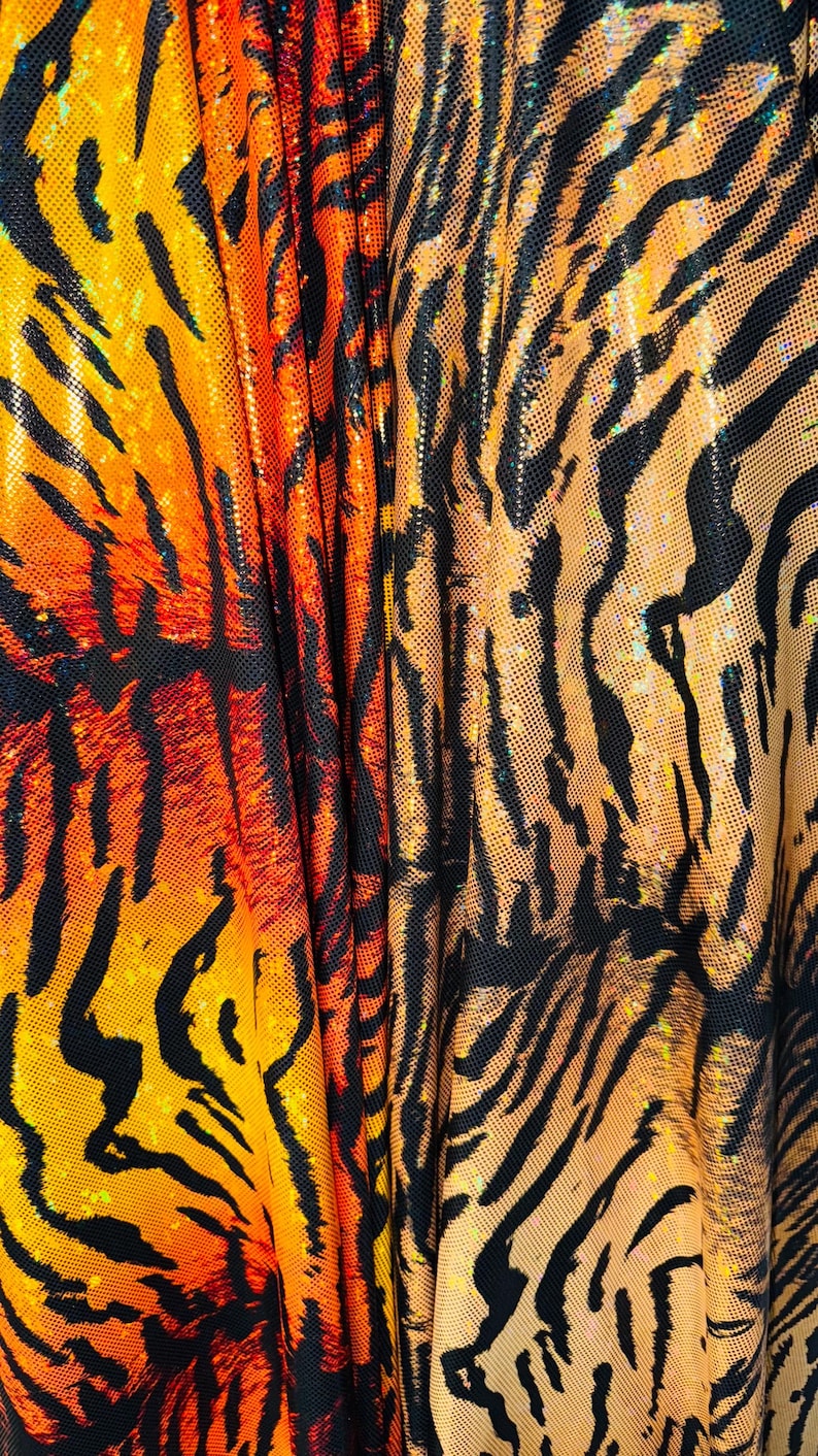 Puede incluir: Primer plano de una tela con estampado de tigre. La tela es naranja, negra y dorada con un acabado brillante.