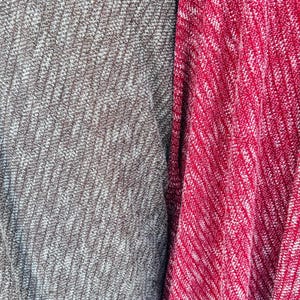 K&ouml;nnte beinhalten: Nahaufnahme von zwei Stoffproben, eine grau mit wei&szlig;en Flecken und die andere rot mit wei&szlig;en Flecken.