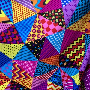 Peut inclure: Un tissu coloré avec un motif patchwork présentant diverses formes géométriques et motifs, notamment des pois, des rayures, des zigzags et des étoiles. Le tissu est composé de différentes couleurs, notamment le rouge, le jaune, le bleu, le vert, le violet et le noir.