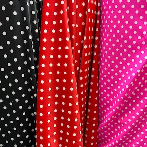 May include: Three fabric swatches with white polka dots on different coloured backgrounds. The swatches are black, red, and pink.