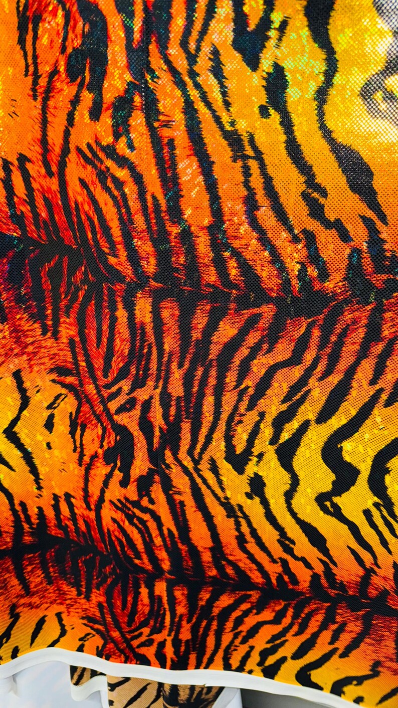 Puede incluir: Primer plano de una tela con un patr&oacute;n de rayas de tigre. La tela es naranja, amarilla y negra. Las rayas son gruesas y audaces.