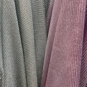 Puede incluir: Primer plano de tres muestras de tela. Las muestras son de color gris claro, gris oscuro y malva. La tela tiene un acabado brillante, met&aacute;lico y un patr&oacute;n texturizado, similar al tejido de punto.