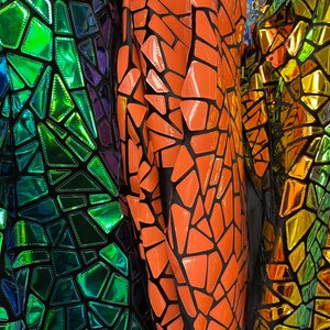 May include: Three pieces of iridescent fabric with a geometric pattern. The fabric is black with green, orange, and gold geometric shapes.