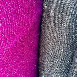 Puede incluir: Primer plano de dos muestras de tela. Una es de color rosa fucsia brillante con una superficie texturizada y tejida. La otra es de color gris oscuro con una superficie texturizada similar.