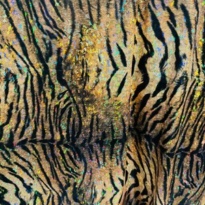 May include: A close-up of a fabric with a tiger stripe pattern. The fabric is brown and black with iridescent glitter accents.