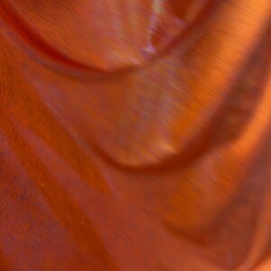 Op de afbeelding: Een levendige oranje stof met een reflecterende, holografische afwerking die subtiele lichtverschuivingen op het oppervlak creëert. Het materiaal is gedrapeerd in zachte, vloeiende plooien, wat de gladde textuur en de metallic glans benadrukt.