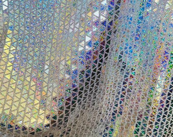 May include: Close-up of a shimmering, iridescent fabric. The material is a silver color with a repeating pattern of small triangles. The triangles catch the light, creating a rainbow effect with hues of blue, green, and yellow.
