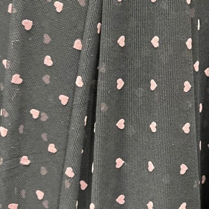 May include: Black sheer fabric with a pink heart pattern. The fabric is folded in half, showing the pattern on both sides.