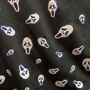 May include: Black fabric with a repeating pattern of white ghost face masks with blue glitter accents.