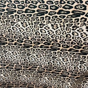May include: Leopard print fabric. The pattern consists of black, irregular spots on a beige background. The fabric appears to be smooth and could be suitable for garments or interior design projects. The print is repeated across the material.