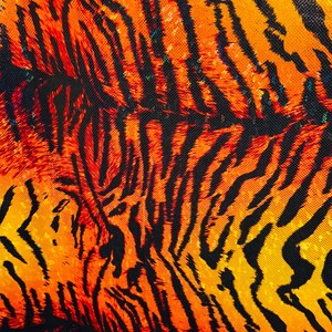 Puede incluir: Primer plano de una tela con estampado de tigre. La tela es naranja, amarilla y negra. El estampado est&aacute; formado por rayas y manchas.