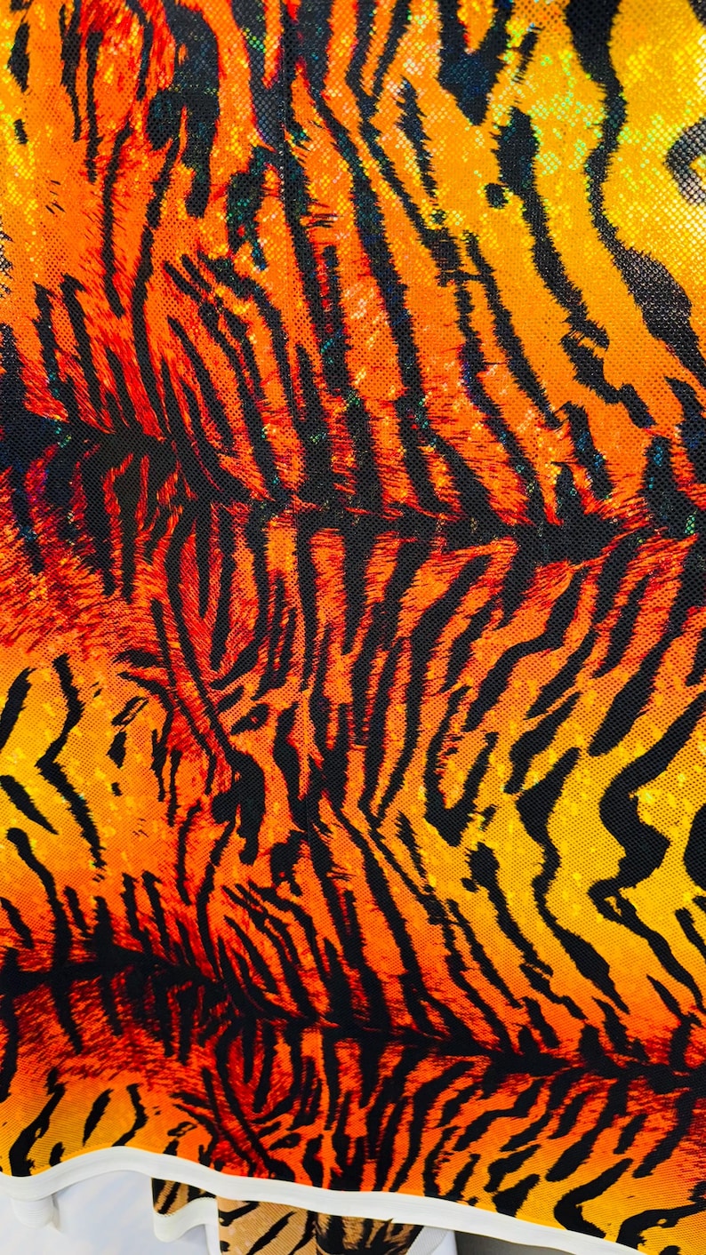Puede incluir: Primer plano de una tela con estampado de tigre. La tela es naranja, amarilla y negra. El estampado est&aacute; formado por rayas y manchas.