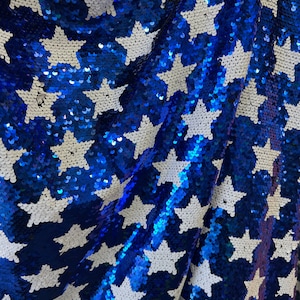May include: Blue and white fabric with a star pattern made of sequins. The fabric is folded and the sequins are shiny.