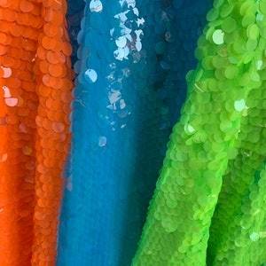 May include: Three fabric swatches with large, round sequins. The swatches are orange, turquoise, and lime green.