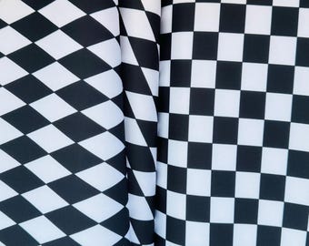 May include: Close-up of two fabric patterns. One features a black and white diamond pattern, while the other displays a classic black and white checkerboard design. The fabrics are draped, showcasing the patterns' textures.