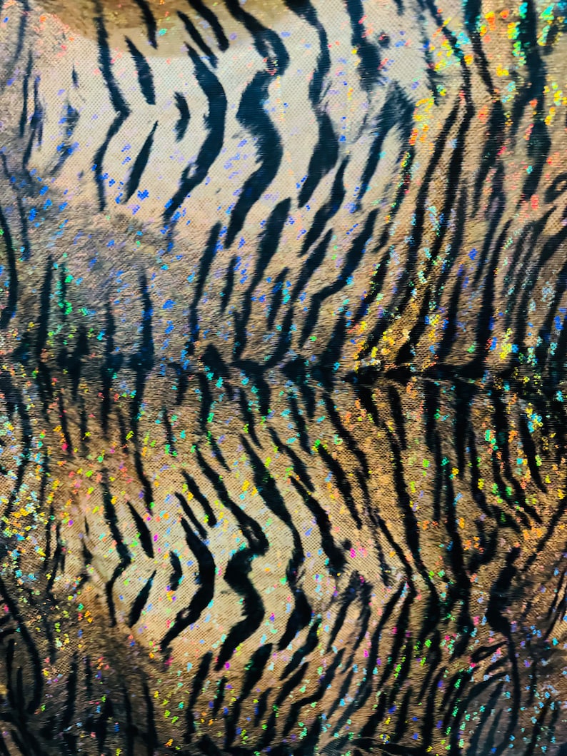 May include: Close-up of a black and brown tiger print fabric with iridescent glitter accents.