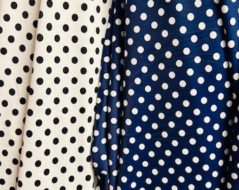 May include: Two fabrics with a polka dot pattern. One is white with black dots, the other is navy blue with white dots. The fabrics are draped, showing the texture and pattern of the material. Ideal for sewing projects.