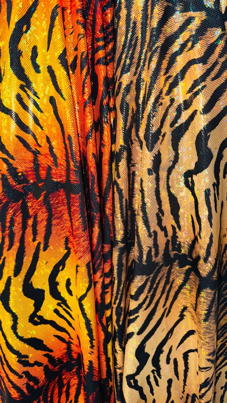 Puede incluir: Tela de estampado de tigre naranja y negro con un acabado brillante. La tela est&aacute; doblada por la mitad, mostrando el patr&oacute;n en ambos lados.