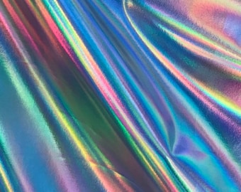 May include: A close-up of iridescent fabric with a holographic finish. The fabric is folded and has a blue, green, and purple colour scheme.