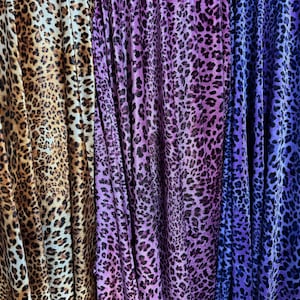 May include: Three fabric swatches with a leopard print pattern. The swatches are brown and white, purple and white, and blue and white.