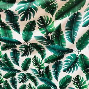 Op de afbeelding: Een witte stof met een herhalend patroon van groene tropische bladeren. De bladeren zijn in verschillende vormen en maten, waaronder grote monstera bladeren en kleinere palmbladeren.