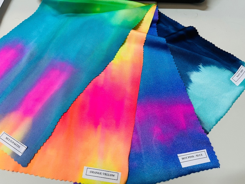 May include: Five fabric swatches with tie-dye patterns in various colors, including blue, green, pink, orange, and yellow. The swatches are labeled with the color combinations: "Multi Pastel", "Orange/Yellow", "Hot Pink/Blue", and "Navy Green".