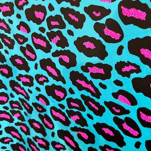 Puede incluir: Una tela azul con un estampado de leopardo negro y rosa.