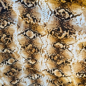 Könnte beinhalten: Nahaufnahme eines braunen und weißen Stoffes mit Schlangenhautmuster.