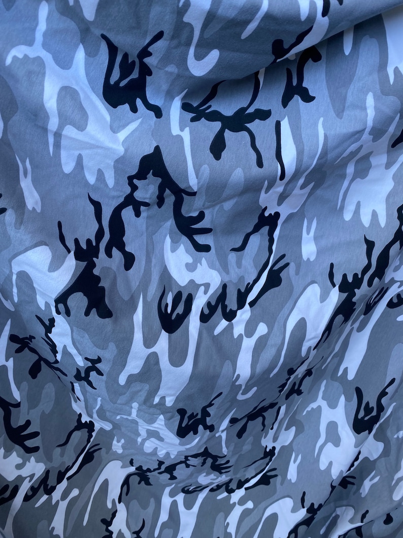 May include: Grey and black camouflage fabric with a wavy pattern.